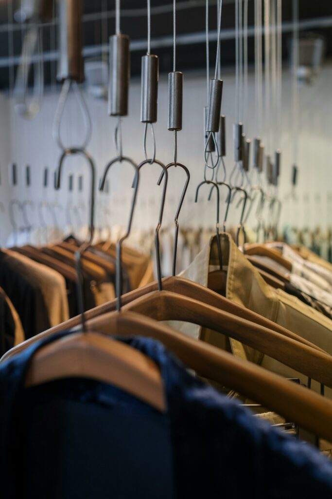 Close-up of a variety of clothes hanging on wooden hangers in a store.